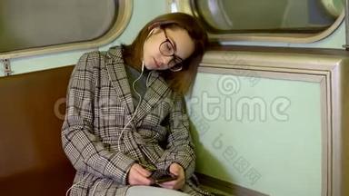 一个<strong>年轻</strong>的女人在地铁<strong>火车上</strong>睡着了。 戴着耳机的女孩。 旧地铁车